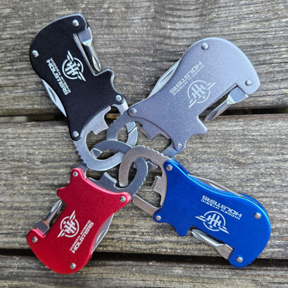 Metallic carabiner with bottle opener, philips screwdriver and letter opener on a wooden surface and brick wall background