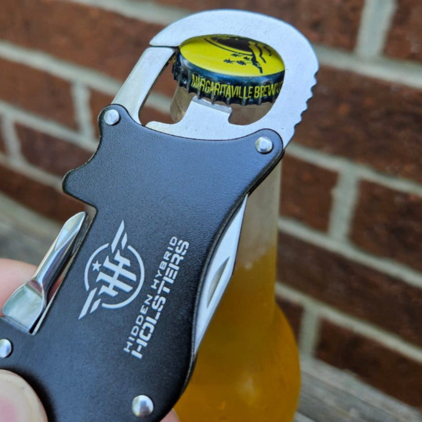 Metallic carabiner with bottle opener, philips screwdriver and letter opener on a wooden surface and brick wall background