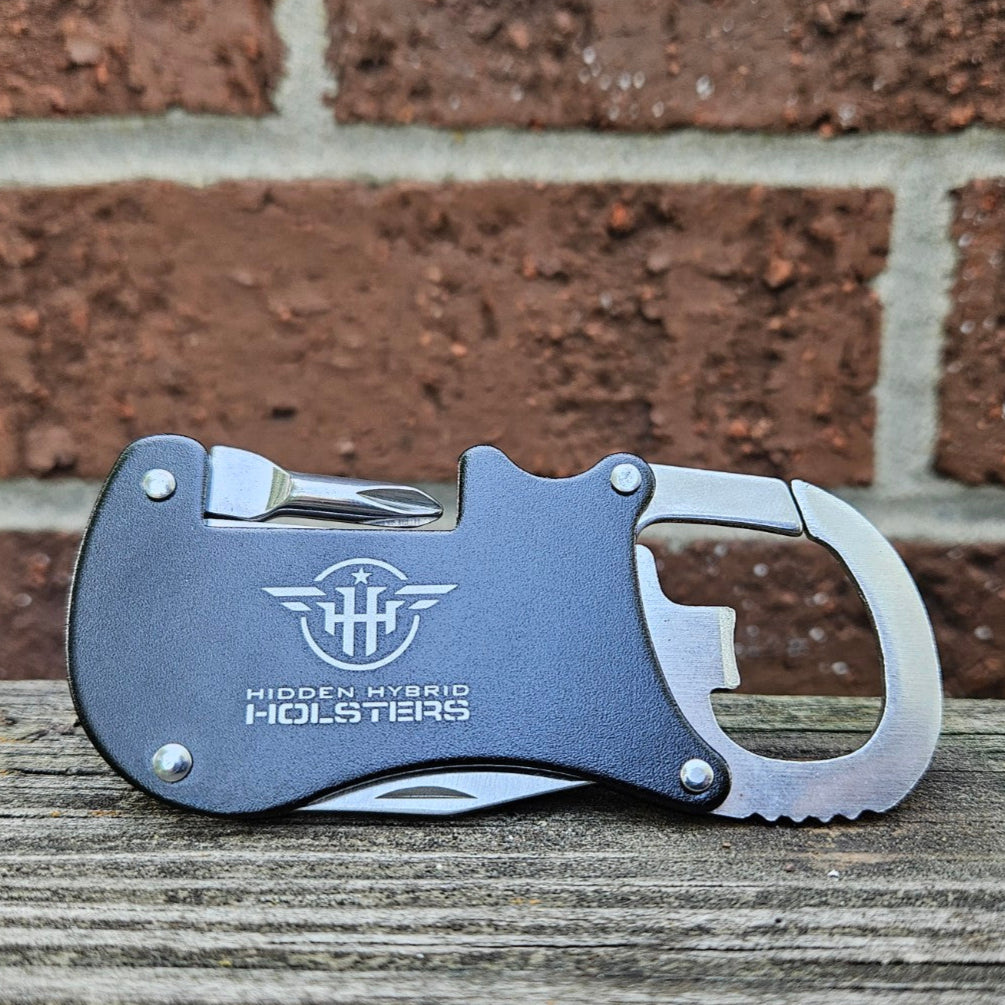 Metallic carabiner with bottle opener, philips screwdriver and letter opener on a wooden surface and brick wall background