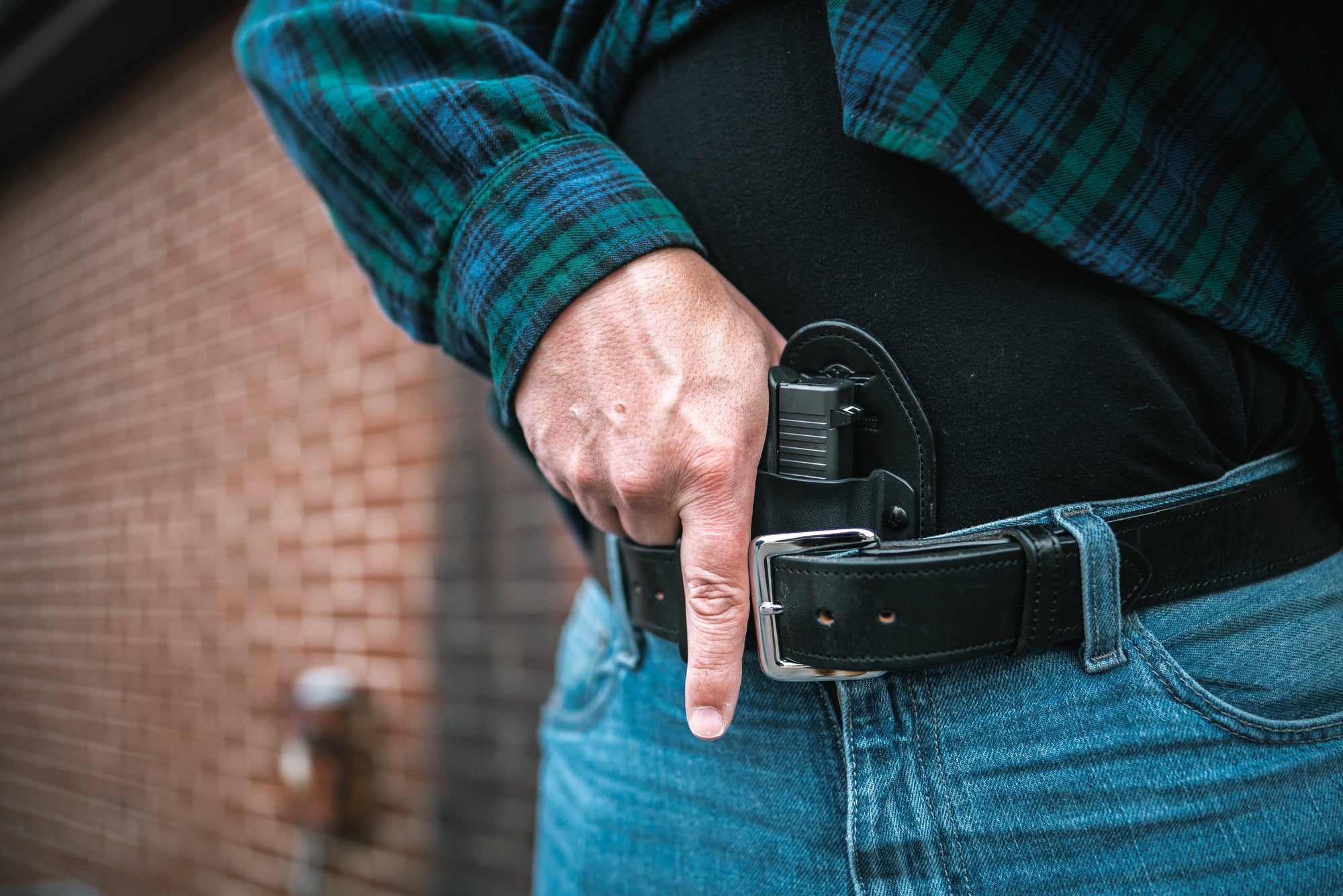 Man in Jeans and Flannel about to draw from a Hidden Hybrid Holsters Appendix Holster